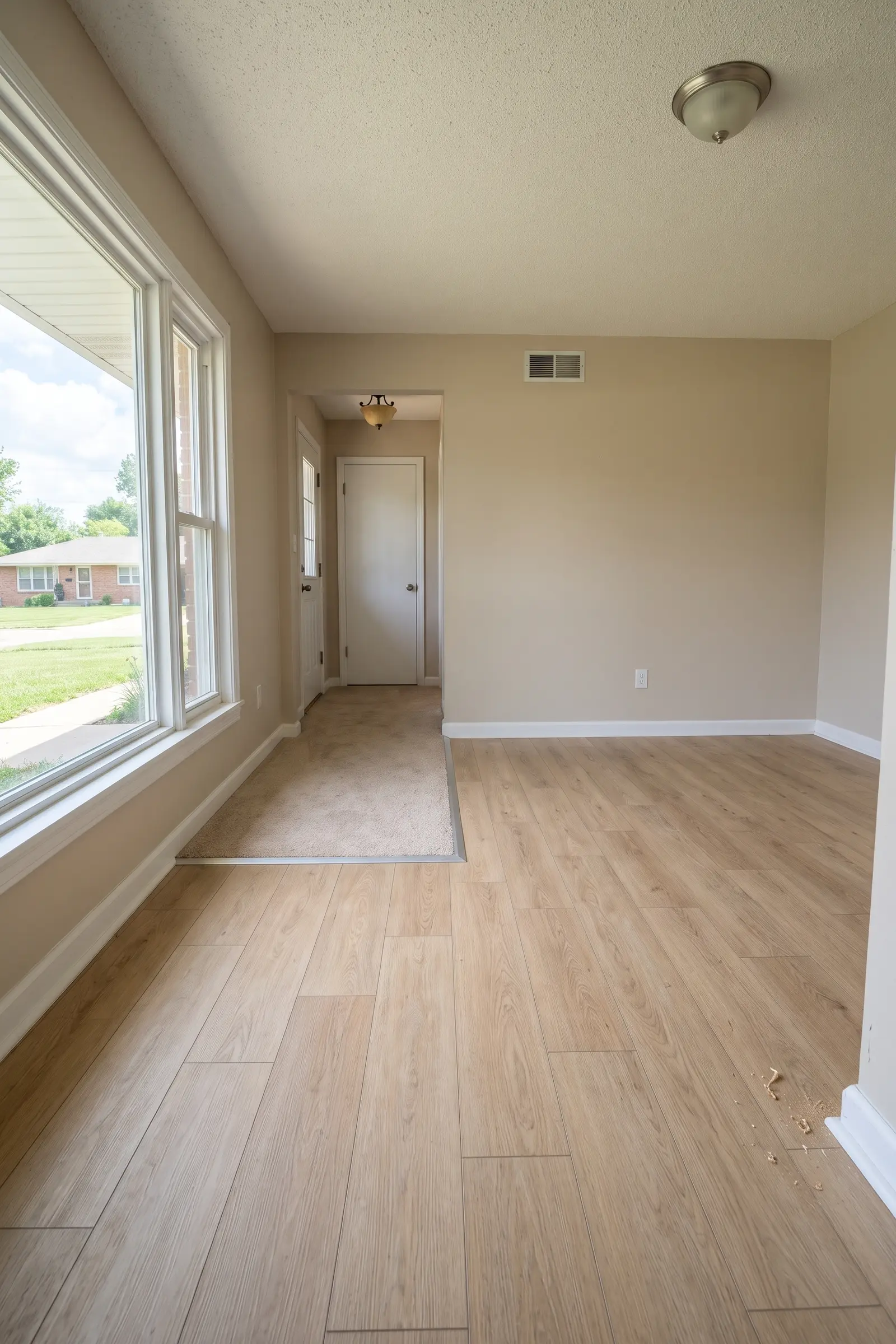 Same room with new light oak-look plank flooring and fresh white baseboard